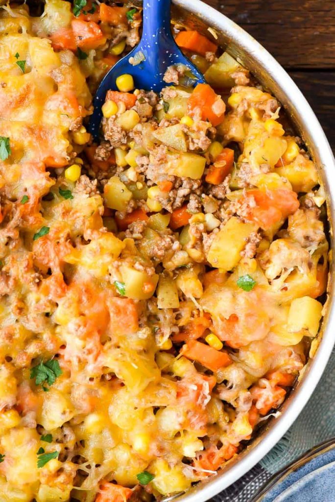 a skillet with ground beef, carrots, and corn casserole topped with cheese