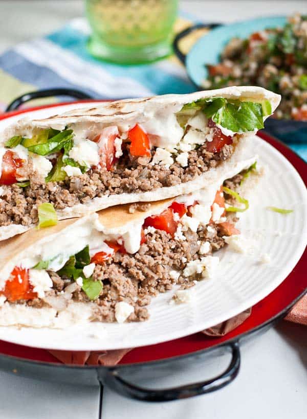 A ground beef stuffed gyro topped with shredded lettuce, diced tomatoes, and tzatziki sauce