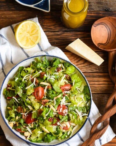 a green salad with parmesan cheese, bacon, and chopped tomatoes