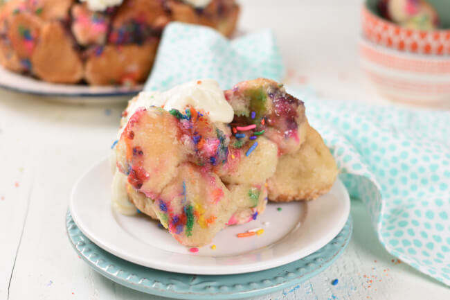 a plate with baked monkey bread, sprinkles, and frosting on top