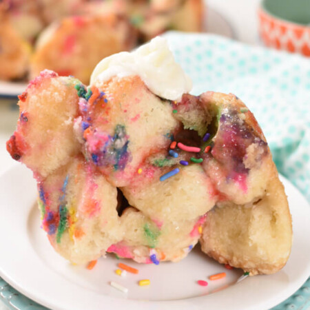 a serving of monkey bread on a pan, with mulit colored sprinkles and icing