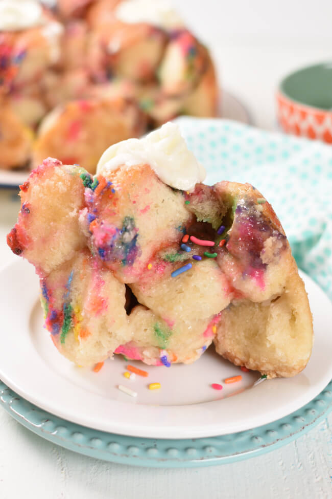 a serving of monkey bread on a pan, with mulit colored sprinkles and icing