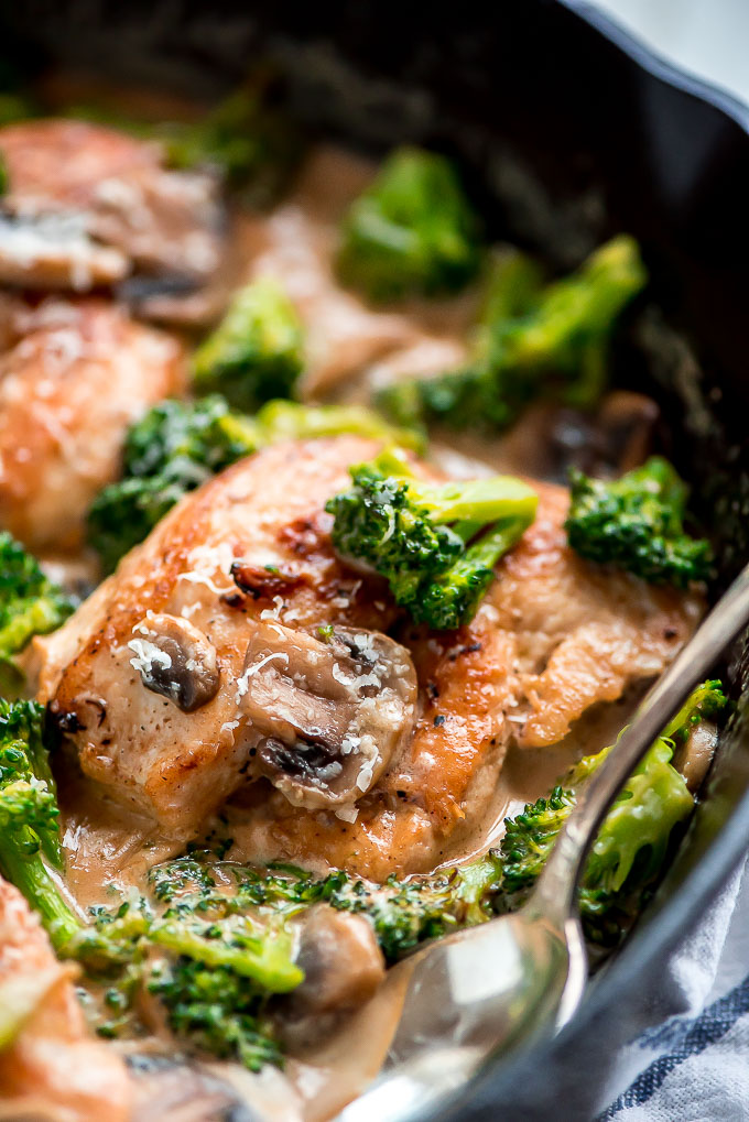 a cast iron skillet with fried chicken smothered in broccoli and mushrooms