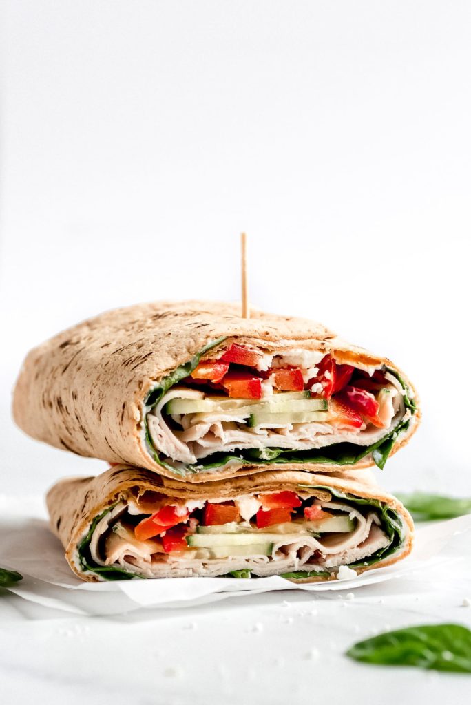 a turkey wrap cut in half filled with red peppers and spinach