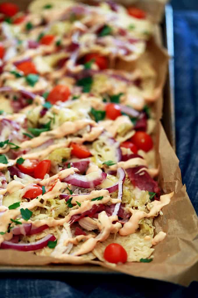 a sheet pan of nachos with chicken, purple onions, tomatoes, and cilantro