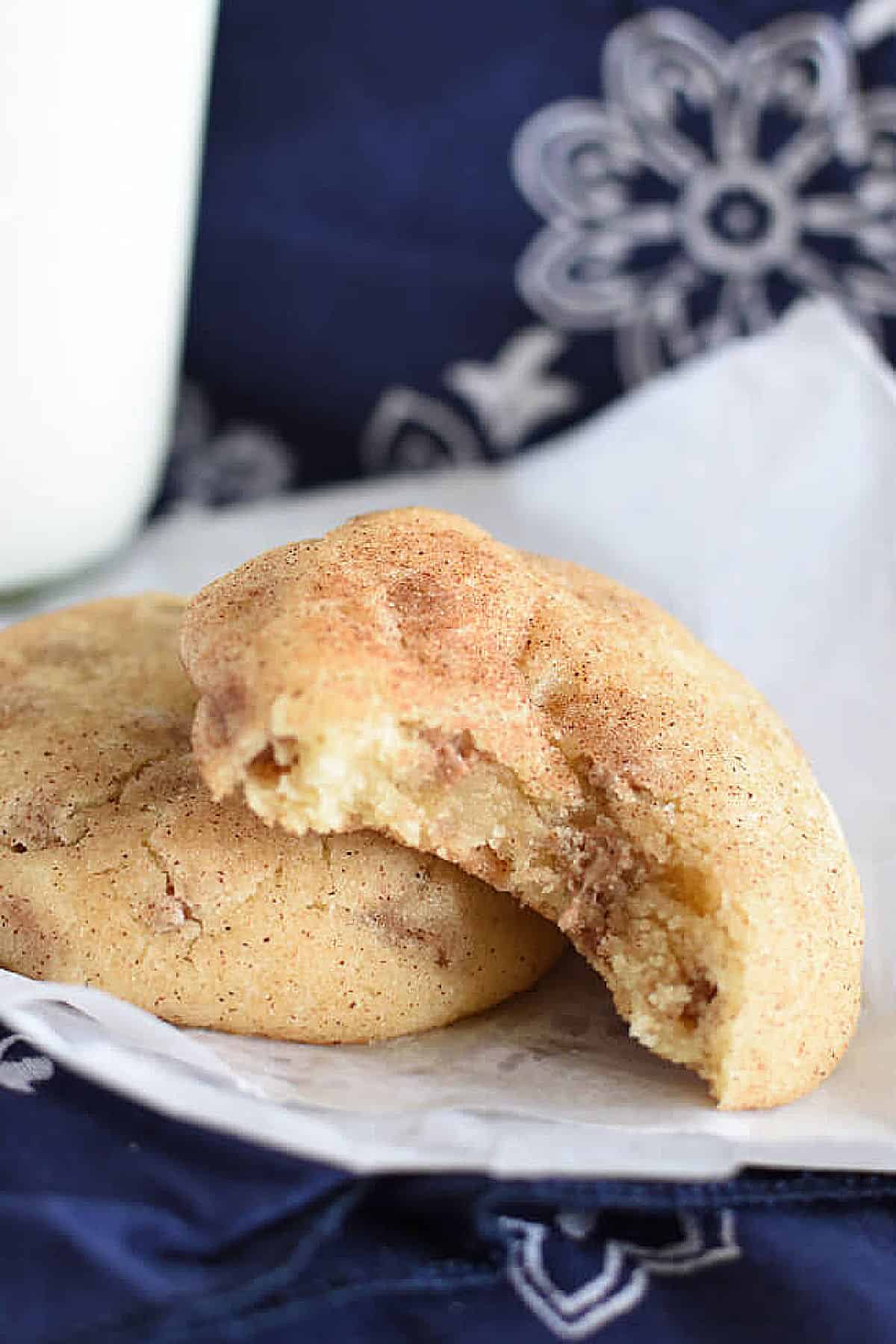 A snickerdoodle cookie with cinnamon chips with a bite taken out of it.
