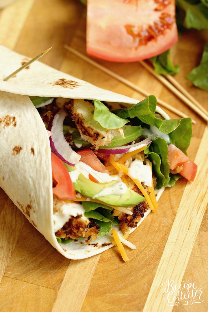 a flour tortilla wrap with chicken topped with avodados, lettuce, and tomatoes