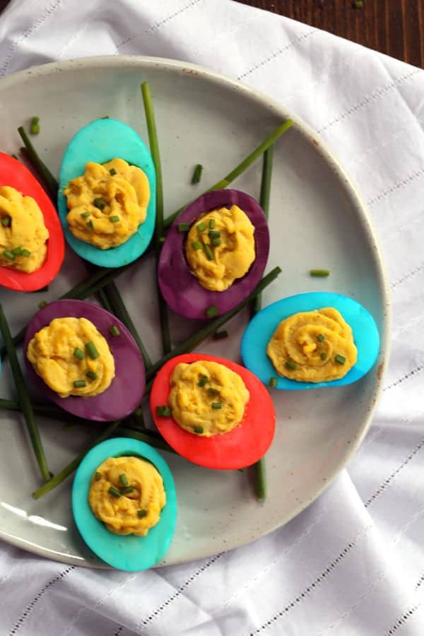 A plate with red, purple, and tourquise dyed eggs