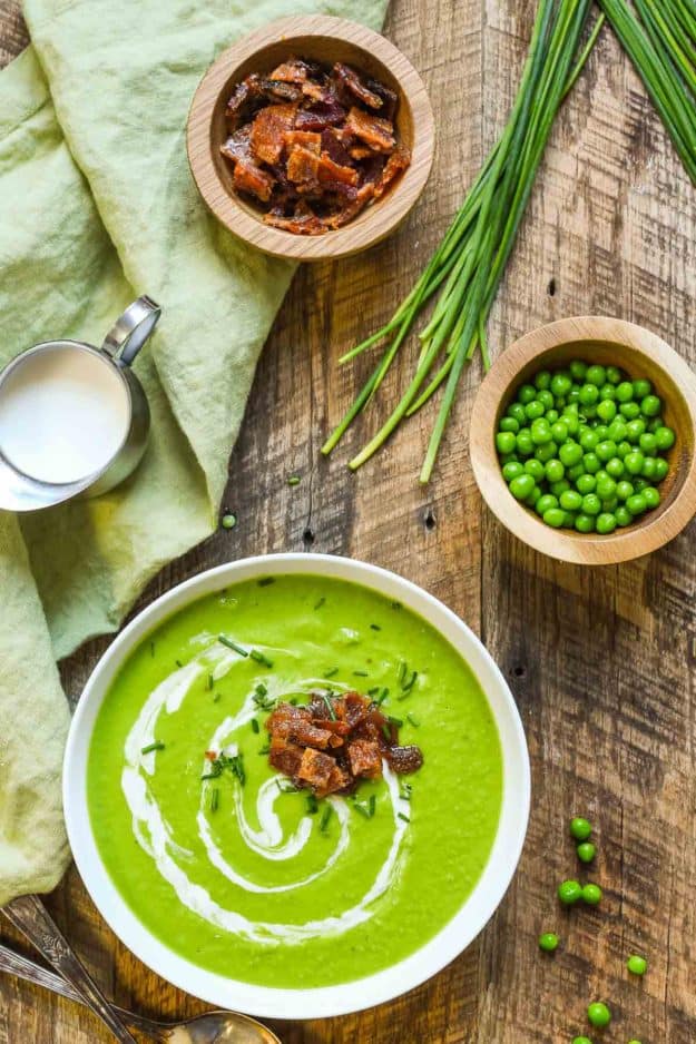 A bowl of bright green soup on a wooden board