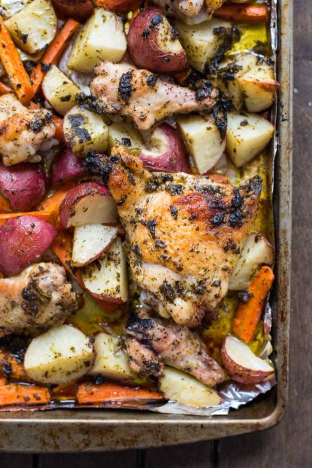 a sheet pan with potatoes, carrots, and chicken thighs