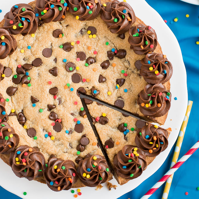 a huge baked cookie with chocolate chips, chocolate icing piped on the edges and sprikles