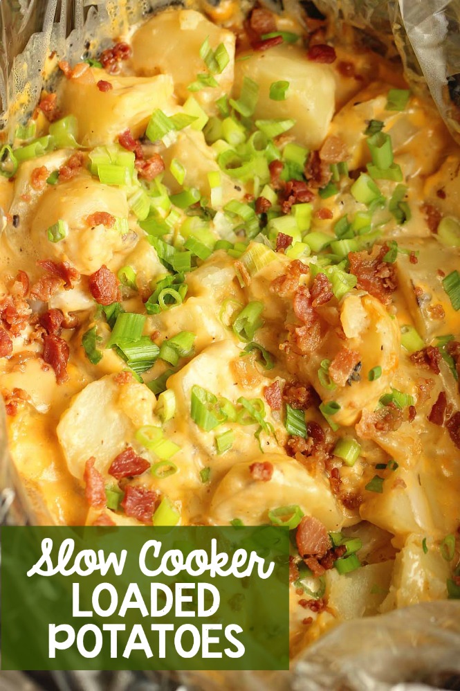 a slow cooker with cooked potatoes tossed in cheese and topped with bacon crumbles and green onions