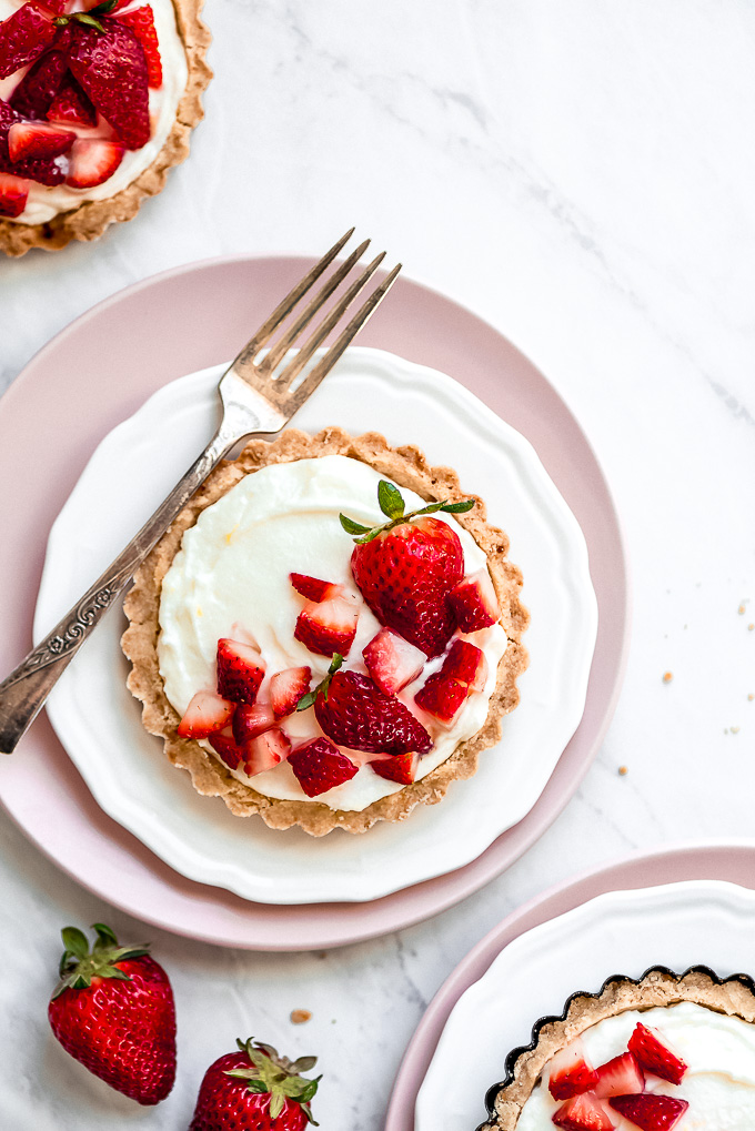 a baked tart filled with white cream and topped with fresh strawberries
