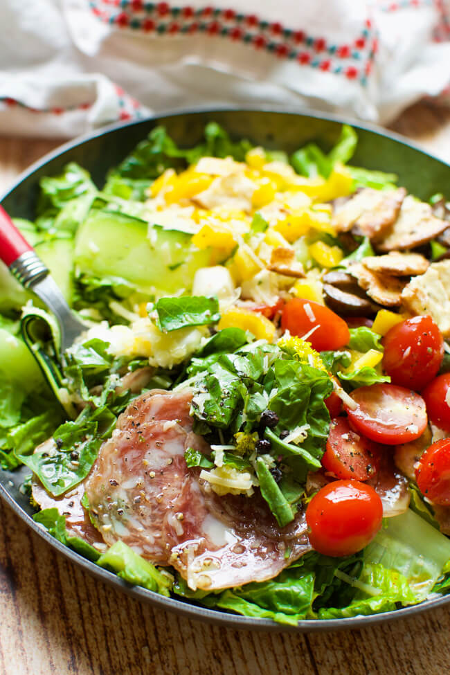 Green salad with tomatoes, olives, salami, and yellow peppers