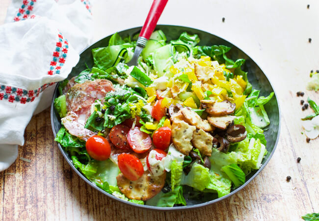 a green salad with lots of toppings in on a black plate