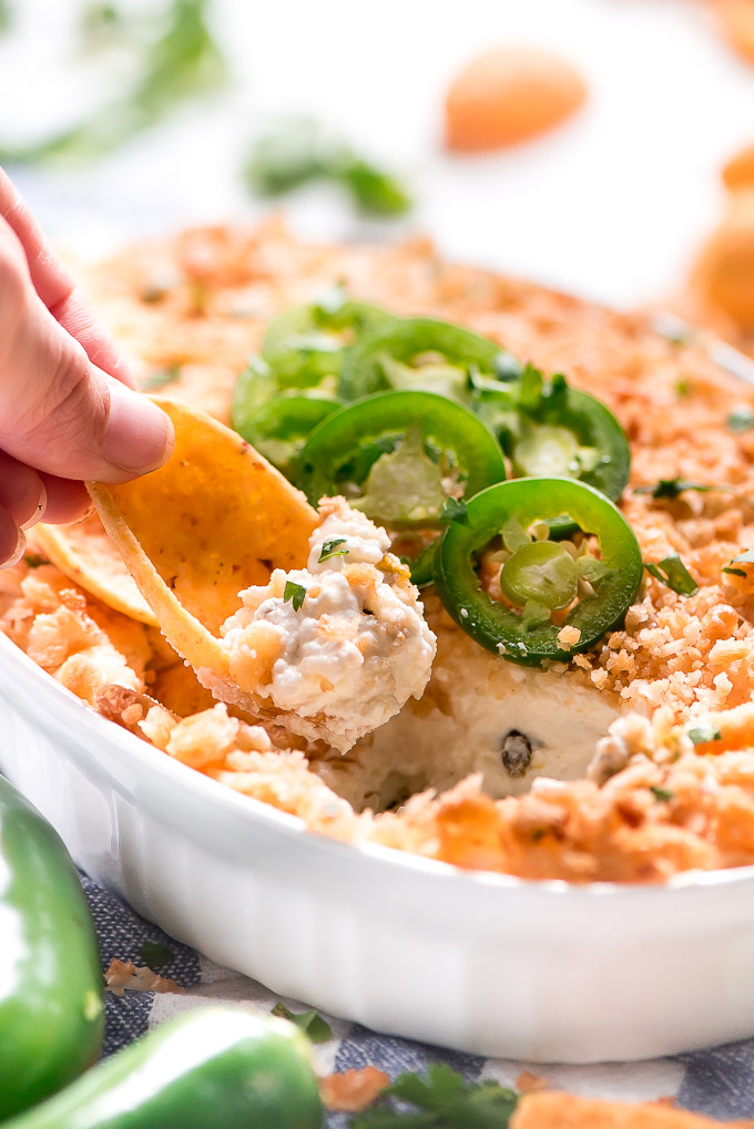 a corn chip scooping jalapeno popper dip from a dish