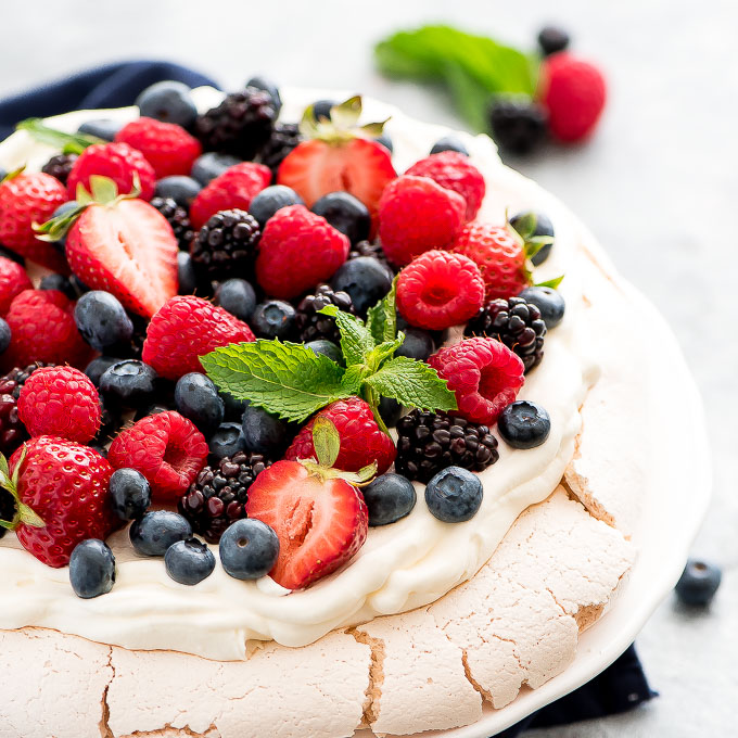 a dessert on a plate topped with fresh blueberries, blackberries, and strawberries