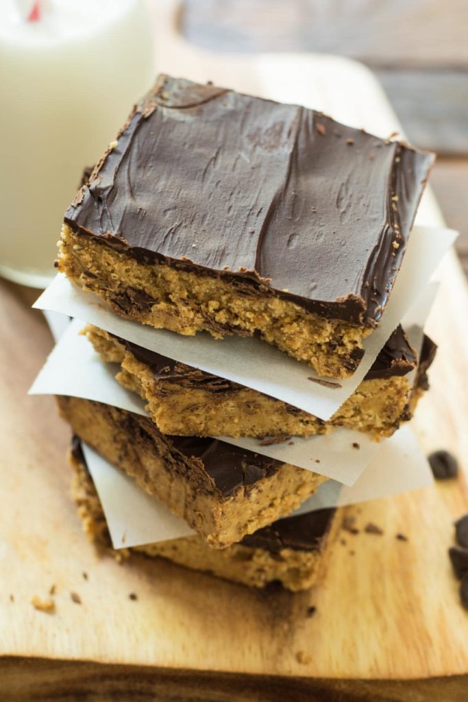 a stack of no bake peanut butter bars with chocolate spread on top