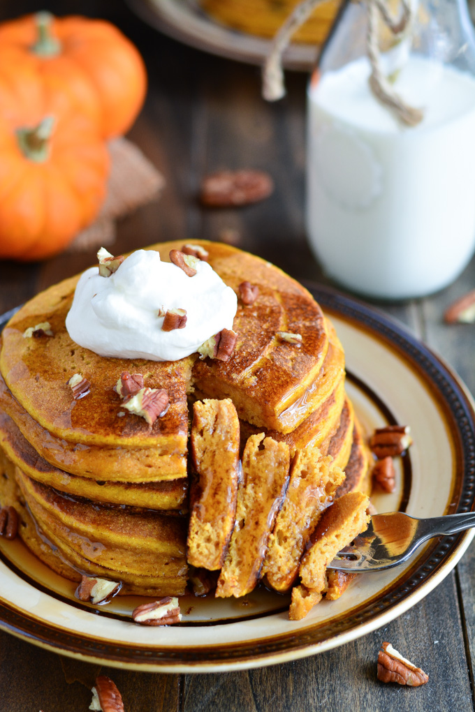 a stack of pancakes topped with whipped cream and pecans