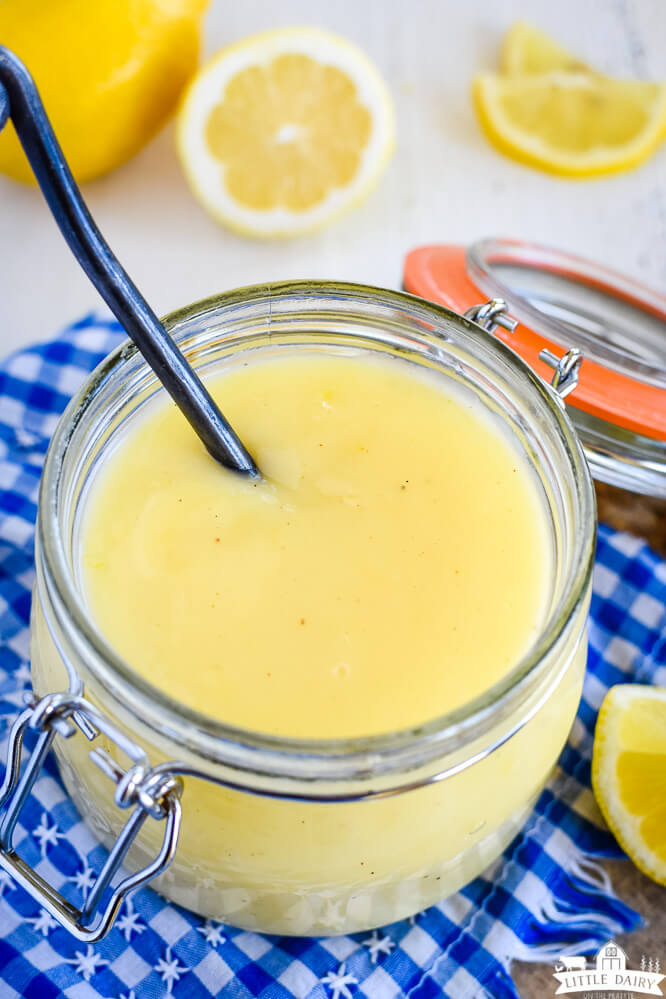 citrus curd in a mason jar with fresh lemon wedges in the background. Little Dairy on the Prairie