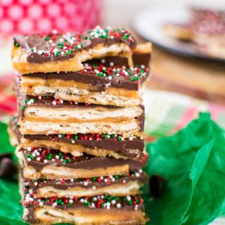 a stack of saltine cracker candy topped with chocolate and red, white, and green sprinkles