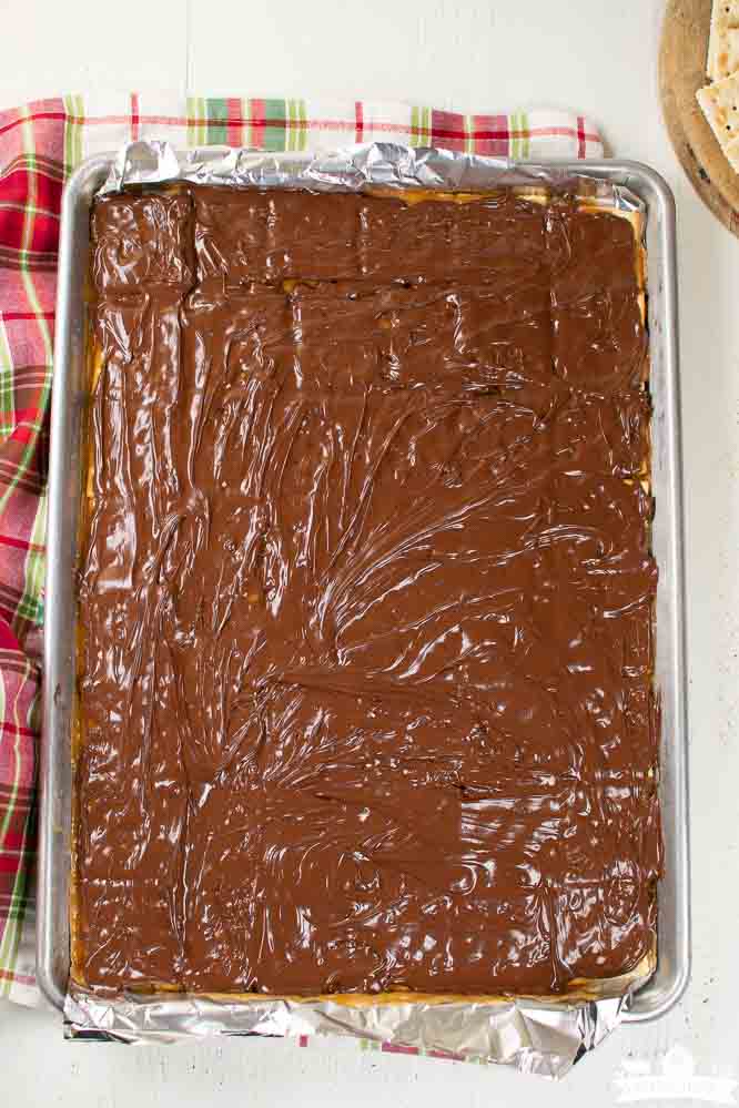 a foil lined sheet pan with layers of saltine crackers, caramel, and melted chocolate