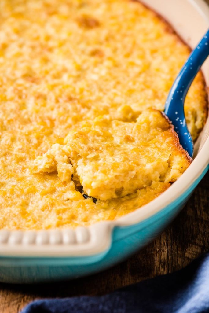a blue serving dish filled with baked corn casserole