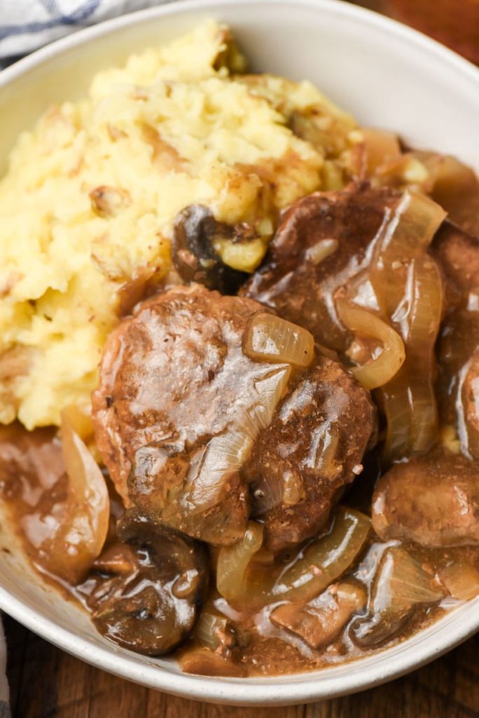 mashed potatoes topped with steak smothered in brown gravy and sauteed onions and mushrooms