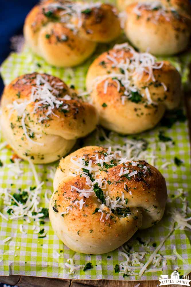 pizza dough tied into a knot and made into garlic knots sprinkled with parmesan cheese and herbs