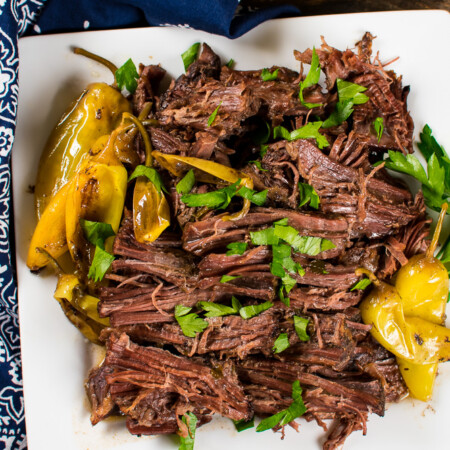an overhead image of shredded roast beef on a plate with banana peppers
