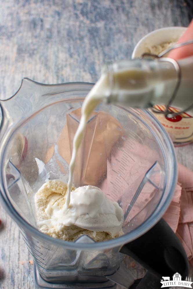 pouring milk into a blender with scoops of vanilla ice cream