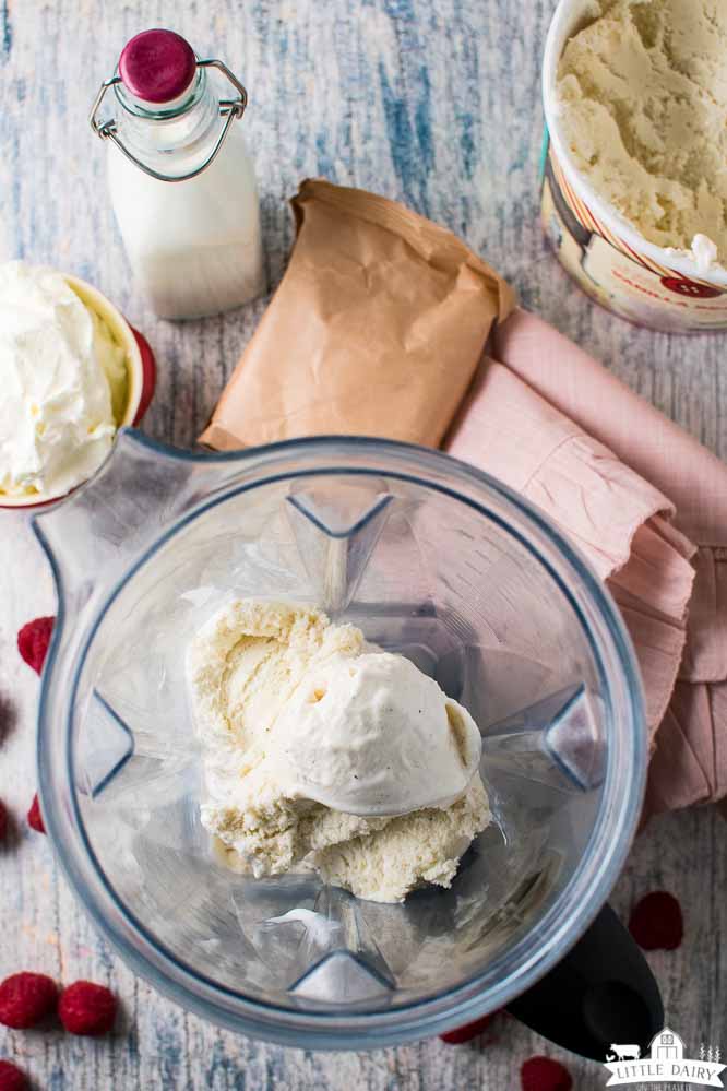 a blender filled with scoops of vanilla ice cream surrounded by milk, jello, and whipped cream