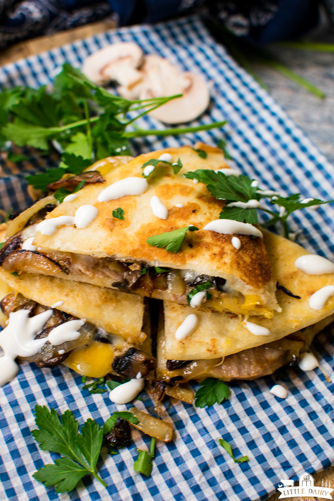 a stack of quesadilla triangles drizzled with sour cream and sprinkled with chopped parsley