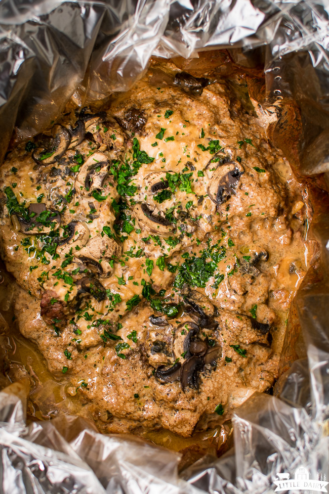 cooked cube steak with mushrooms in gravy all in a black crockpot