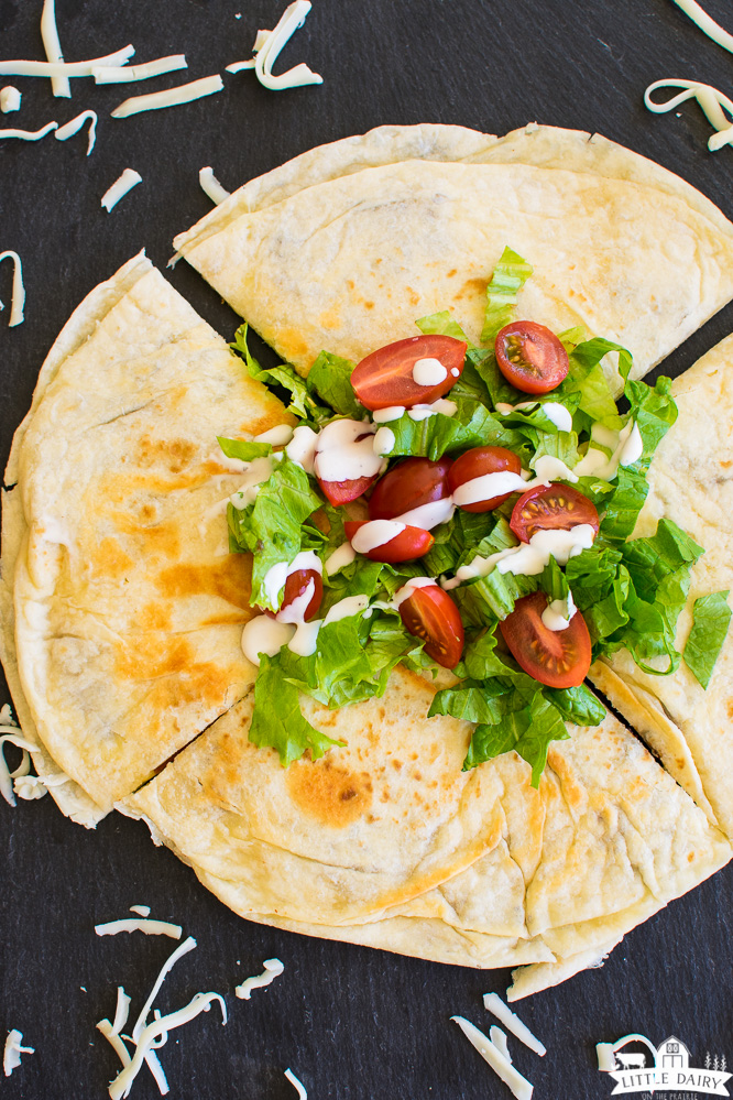 a whole quesadilla cut into quarters, topped with tomatoes and lettuce