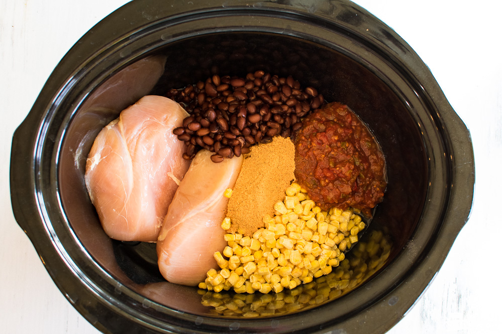crock-pot with raw chicken breasts, black beans, corn, salsa, and seasonings