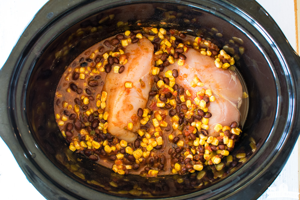 slow cooker with chicken breasts, corn, and beans