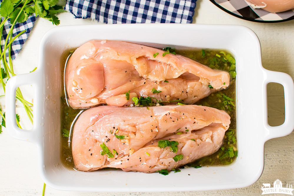 two chicken breasts soaking in an herb marinade