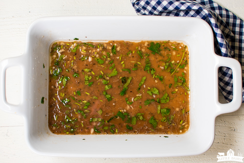 brown meat marinade with chopped cilantro in a white baking dish