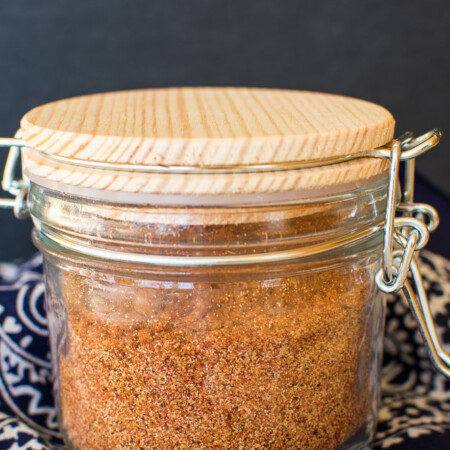 a glass jar with a wooden lid filled with barbecue rub seasonings