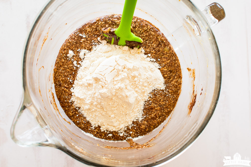 creamed butter, sugar, and cocoa topped with flour in a glass mixing bowl