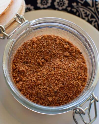 Dry bbq chicken rub in a glass jar with a wooden lid.