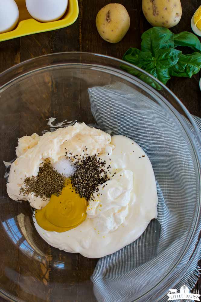 a clear bowl with Greek yogurt, mustard, spices, and milk