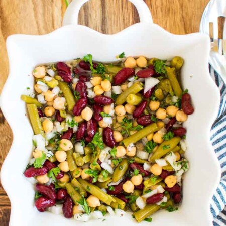 a white dish with kidney beans, garbanzo beans, and green beans in an italian dressing