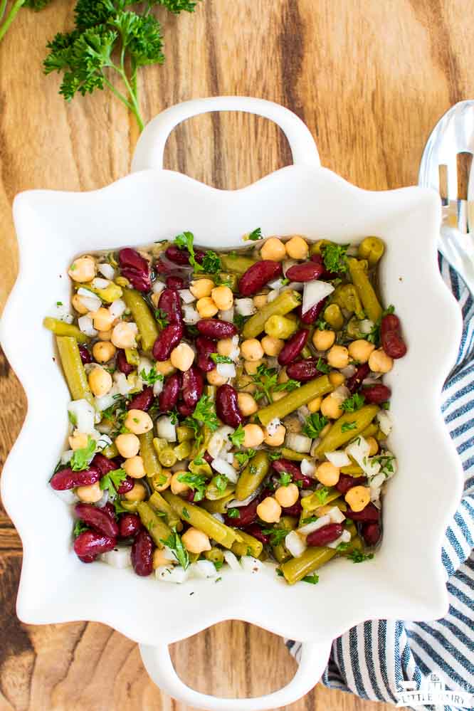 a white dish with kidney beans, garbanzo beans, and green beans in an italian dressing