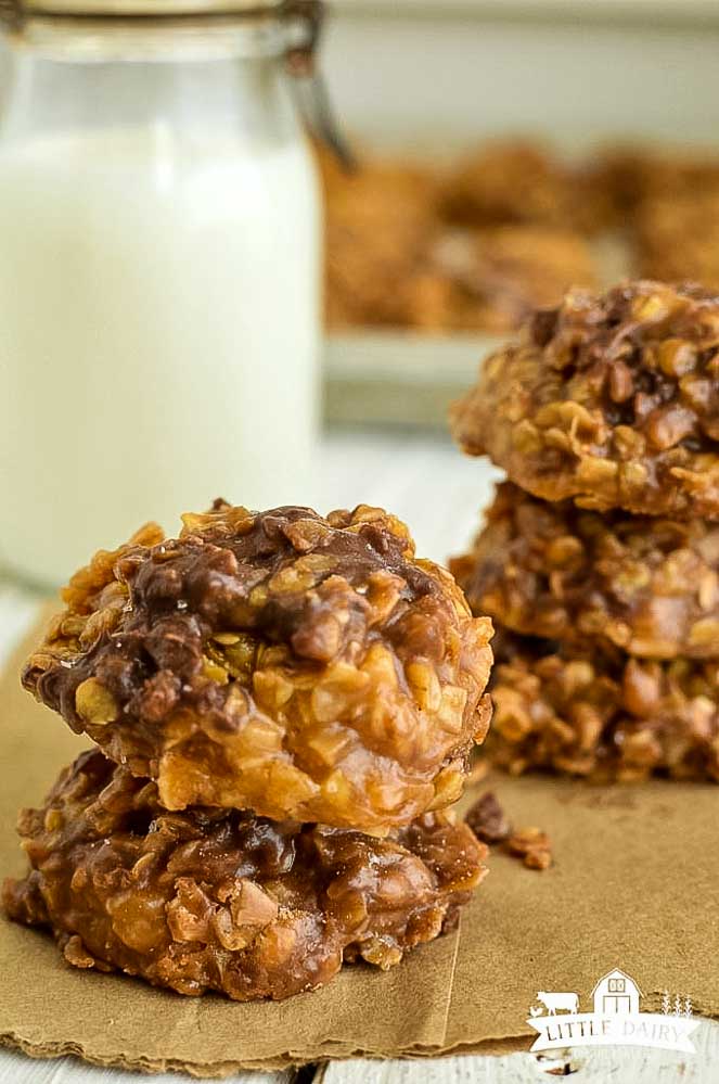 two no bake cookies stacked on top of each other and a glass of milk in the background