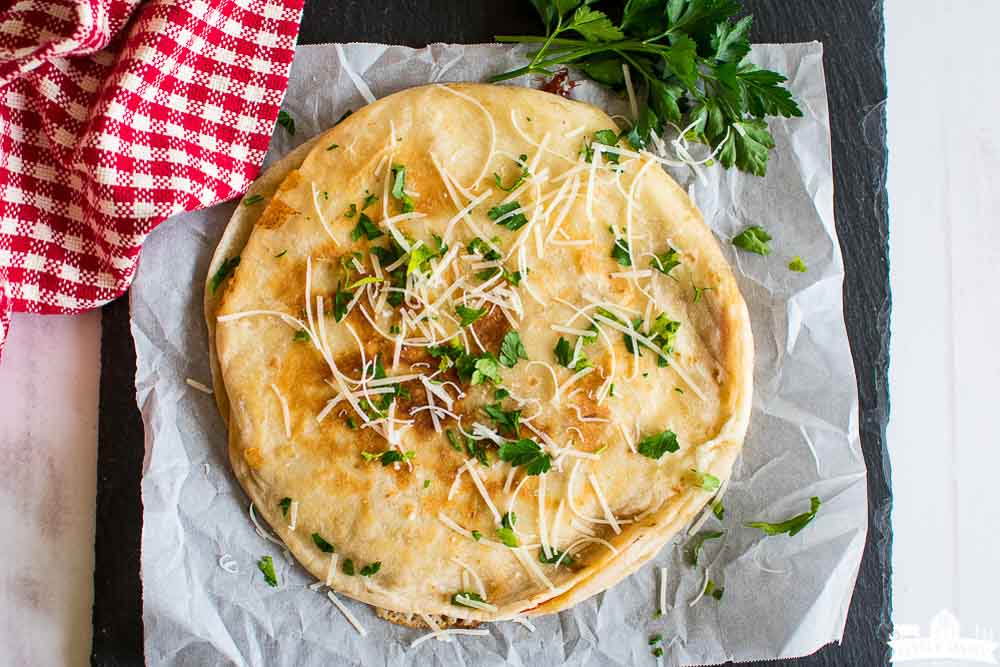 a crispy brown quesadilla topped with herbs and grated cheese