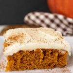 a pumpkin square on a white plate with cream cheese icing, sprinkled with ground nutmeg
