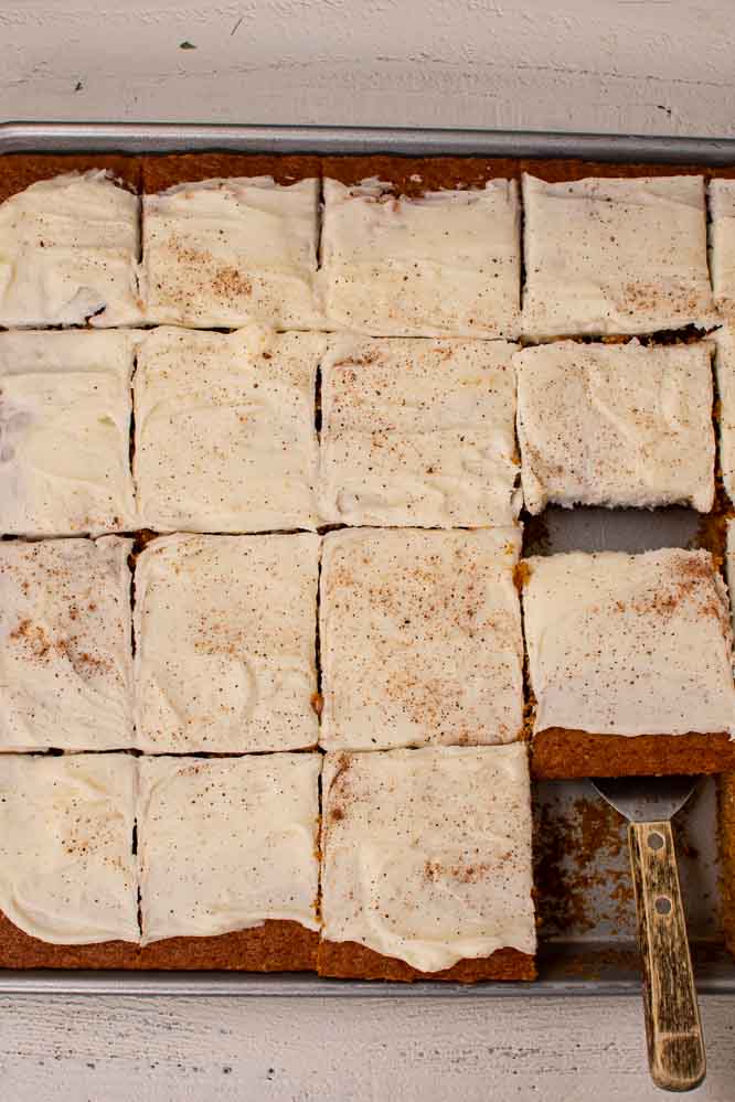 pumpkin bars in a sheet pan, cut into squares, frosted with cream cheese icing