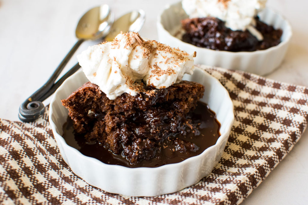 Two dishes with hot fudge pudding cake topped with whipped topping.